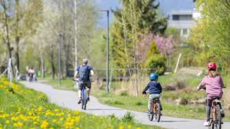 Familie radelt auf dem Frühlingsradweg im Naturpark Haberfeld, umgeben von blühenden Wiesen und Bäumen.