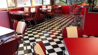 Innenraum des 1950 American Diner mir roten Tischen und schwarz-weissem Boden