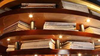 Holzregal mit illuminierten Büchern als Deckenverkleidung