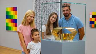 Familie betrachtet eine gläserne Vitrine mit goldener Skulptur im Kunstmuseum Liechtenstein