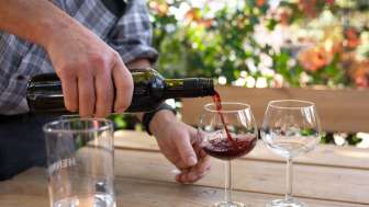 Rotwein wird aus einer Flasche in ein Weinglas gegossen