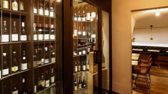 Moderner Weinschrank mit edlen Flaschen in der stilvollen WY Weinbar, Blick in den angrenzenden Verkostungsraum.