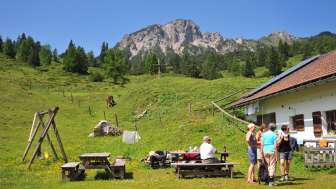 Blick auf die Berge von der Alpe Guschg an der mehrere Personen Pause machen und genießen