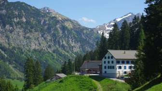 Traditionelles Alp- und Berggasthaus Sücka in Liechtenstein, eingebettet in eine grüne Berglandschaft