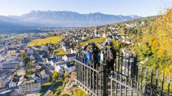 Wanderer am Geländer des Aussichtspunktes Känzile mit Panoramaausblick auf Vaduz und die umliegenden Berge.