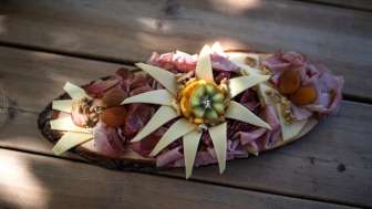 Ein kunstvoll angerichtetes Holzbrett mit verschiedenen Wurstsorten und Käse