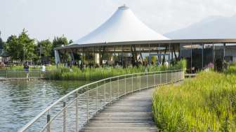 Moderner Pavillon am Wasser in der Freizeitanlage Grossabünt, umgeben von Natur und mit Blick auf die Alpen