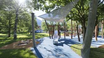 Spielplatz mit verschiedenen Klettergeräten, umgeben von Bäumen