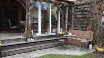 Gemütlicher Sitzbereich im Garten des Studios in Eschen mit Holzbank und Blick zur Terrasse.
