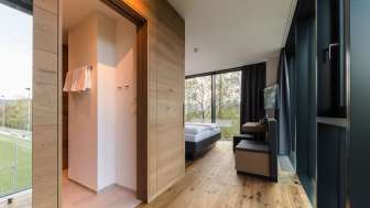Helles Zimmer im Hotel kommod mit elegantem Holzboden und Blick ins Grüne