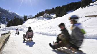 Lehrer Personen rodeln die Rodelstrecke an einem schönen sonnigen Tag in der Winterlandschaft