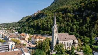 Drohnenaufnahme der Kathedrale St. Florin in Vaduz mit Schloss Vaduz im Hintergrund