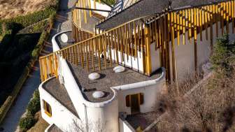 Luftaufnahme des kunstvoll geschwungenen Daches und der goldenen Fassadenelemente des Centrum für Kunst in Vaduz.