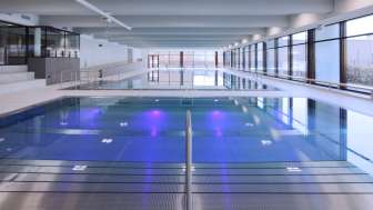Modernes Hallenbad in Triesen mit beleuchtetem Schwimmbecken und großzügiger Glasfront.
