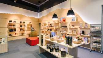 Helles Besucherzentrum mit modernen Holzregalen, gefüllt mit Souvenirs und lokalen Produkten