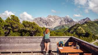 Frau geniesst den Weitblick auf die umliegenden Berge von der Terrasse des Sareis Bergrestaurants