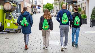 Vier Personen mit grünen FoodTrail-Rucksäcken spazieren durch das Städtle in Vaduz
