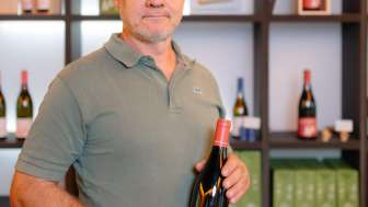 Harry Zech präsentiert eine Flasche seines Weins im stilvollen Verkaufsraum – regionale Weinkultur aus Liechtenstein.