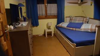 chlafzimmer im Studio in Eschen mit Bett, TV, Kommode und Fenster mit Vorhängen.