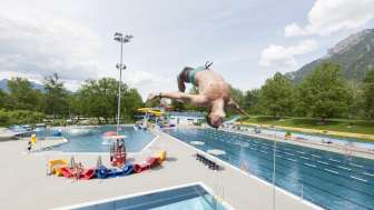 Junge macht einen Salto vom Sprungturm ins Becken