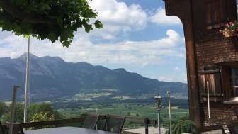 Traditionelles Gebäude mit sonniger Terrasse und Bergpanorama im Hintergrund
