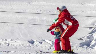 Skilehrerin fährt gemeinsam mit einem Kind mit dem Tellerlift