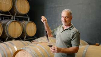 Harry Zech entnimmt Wein zur Verkostung mit einer Pipette aus dem Barriquefass – traditionelle Weinherstellung in Schaan.