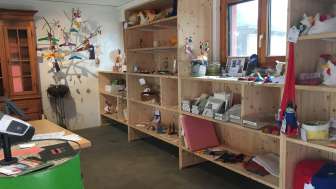 Innenraum des Birkahoflädile mit Holzregalen voller regionaler Produkte, dekorativ gestaltet mit bunten Elementen – Hofladen in Liechtenstein.