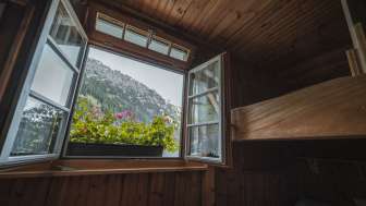 Fensterblick aus dem Schlafraum: Blick aus einem einfachen Schlafraum mit Stockbett der Gafadurahütte auf die Berglandschaft