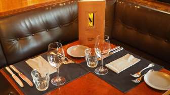 Gedeckter Tisch mit Speisekarte im Leder-Sitzbereich des Vanini Cafés