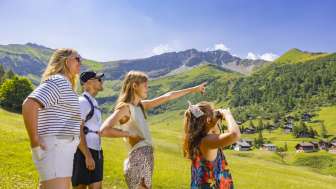 Familie schaut in die Ferne in der alpinen Landschaft mit Blick auf die Berge im Sommer