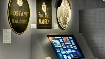Museumsraum mit alten Postschildern und einem digitalen Display zur Geschichte der Post in Liechtenstein