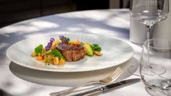 Hauptgericht mit saftigem Fleisch, frischem Gemüse und dekorativen Blüten