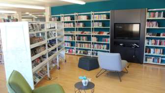 Gemütliche Leseecke in der Liechtensteinischen Landesbibliothek mit Sesseln und Medienwand zwischen hohen Bücherregalen