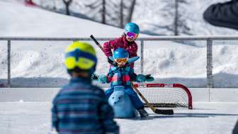 Familie beim Schlittschuhlaufen und Eisstockschiessen in Malbun