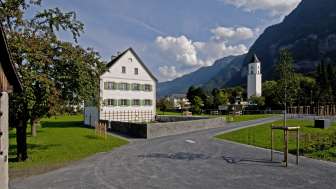 Historischer Pfarrhof mit weisser Fassade und grünen Fensterläden
